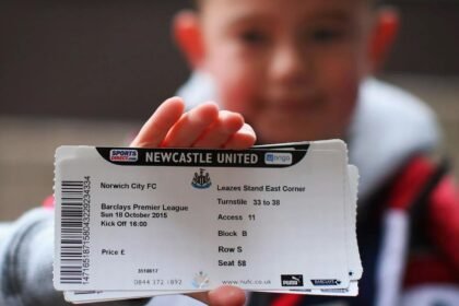 A boy holding football tickets in his hand