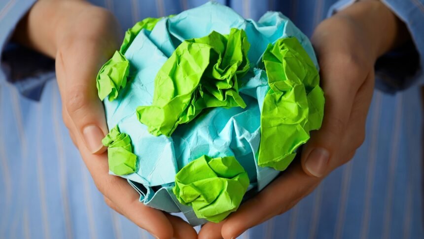 A person holding a paper globe representing efficient ways of waste management for a better tomorrow